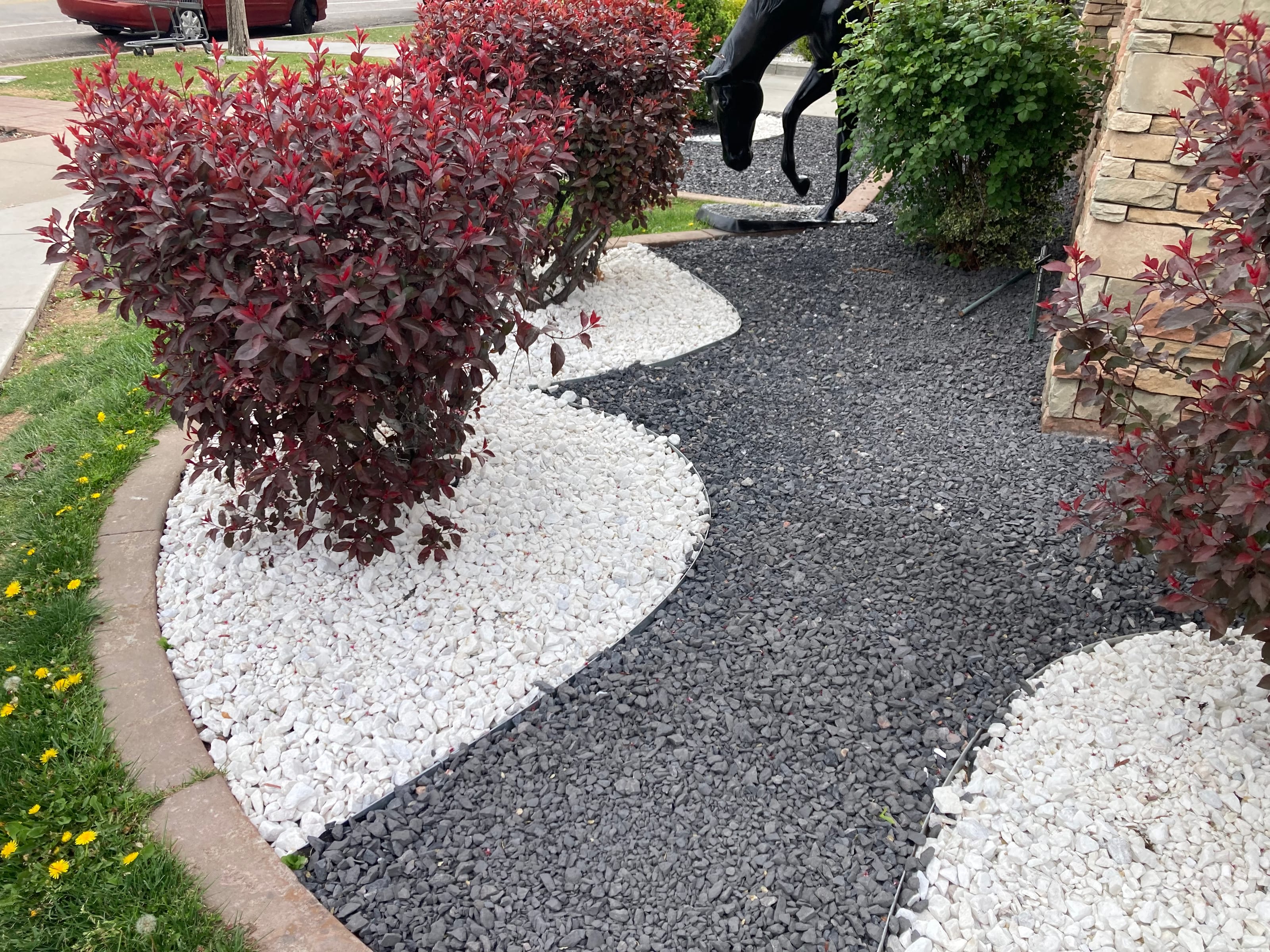 Decorative rock landscaping with white and dark rock around shrubs and landscape beds