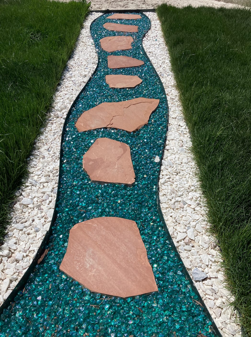 Decorative walkway landscaping with colored rock and stepping stones