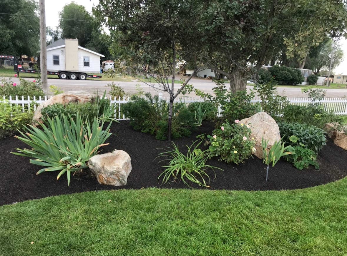Finished front yard xeriscape with decorative rock, low-water plants, boulders, and clean planting beds in Syracuse Utah